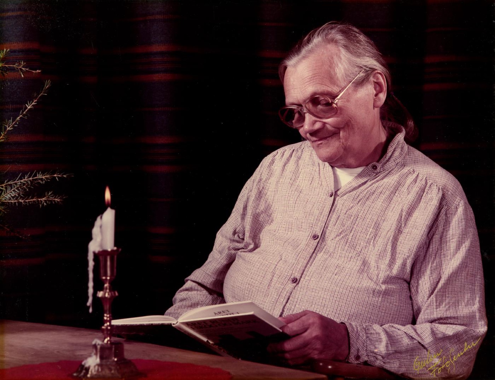 Ingeborg Tynning Brekke leser i en bok ved levende lys